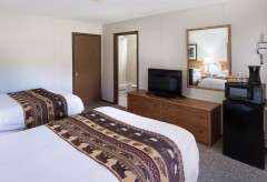 Room with two beds, tv, and view into bathroom
