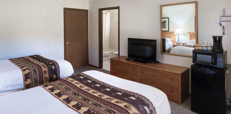 Room with two beds, tv, and view into bathroom