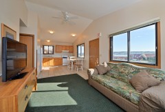 View of living room with sofa and tv with kitchen in the background
