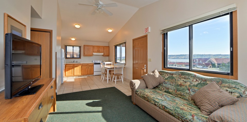 View of living room with sofa and tv with kitchen in the background